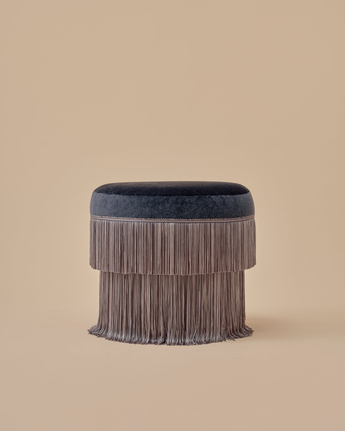 Siro Ottoman by Love House x Spencer Malinski, front view of the round upholstered top and tiered fringe skirt, available at Love House New York